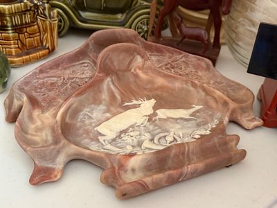 Sale Photo Thumbnail #28: Vintage molded slag glass ash tray set with embossed deer and hunting scenes, featuring swirling pink and white tones.