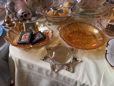 Sale Photo Thumbnail #53: Collection of vintage glassware and religious items, including marigold carnival glass bowls, small religious icons, and a star-shaped glass dish with a magnifying dome centerpiece.