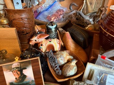 Sale Photo Thumbnail #146: Collection of vintage knick-knacks and collectibles, including a John Wayne portrait frame, ceramic animal figurines, a wooden shoe last, and stoneware crocks.