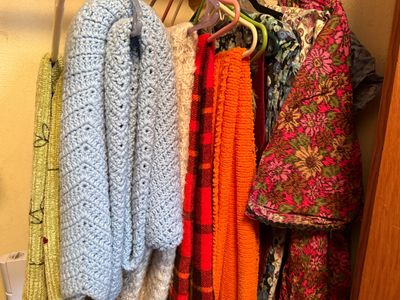 Sale Photo Thumbnail #111: Collection of vintage hand-knit crocheted blankets, shawls, and printed textiles hanging in a closet.