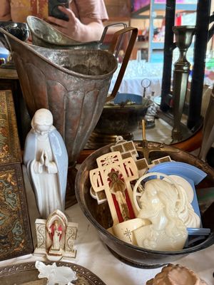Sale Photo Thumbnail #19: Collection of vintage religious items, including a porcelain Madonna figurine, a bowl filled with plastic and metal crucifixes, and a tall weathered metal pitcher.