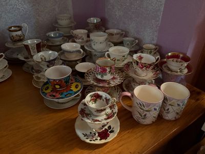Sale Photo Thumbnail #106: Large collection of vintage teacups and matching saucers in various floral, gilded, and colorful porcelain designs, displayed alongside a pair of modern ceramic mugs.