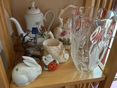 Sale Photo Thumbnail #35: Collection of decorative porcelain teapots, a heavy molded glass vase, ceramic rabbit figurine, Halloween ghost figurine, and miniature gemstone bonsai tree displayed on wooden shelving.