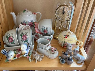 Sale Photo Thumbnail #36: Collection of vintage porcelain items on a wooden shelf, including a floral teapot and matching teacups, small animal figurines, a ceramic shoe, and a glass-dome anniversary clock.