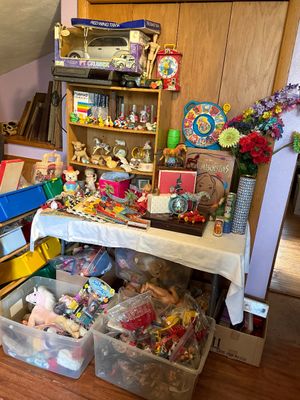 Sale Photo Thumbnail #96: Collection of vintage toys, books, and collectibles, including a boxed PT Cruiser toy, Disney Pocahontas items, plastic storage bins of toys, and small shelf decor.
