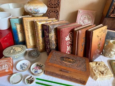 Sale Photo Thumbnail #13: Collection of antique decorative items, featuring embossed photo albums, carved wooden trinket boxes, and small porcelain pin dishes.