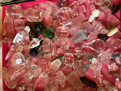 Sale Photo Thumbnail #57: Large collection of vintage crystal and glass bottle stoppers in various shapes, sizes, and colors, displayed in a pink lined box.