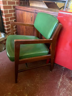 Sale Photo Thumbnail #152: Mid-century modern armchair featuring a dark wood frame with angular arms and green vinyl upholstery.