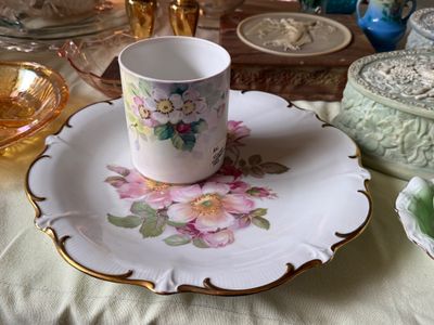 Sale Photo Thumbnail #52: Hand-painted floral porcelain mug sitting on a matching scalloped cake plate with gilt trim, surrounded by vintage glassware and trinket boxes.