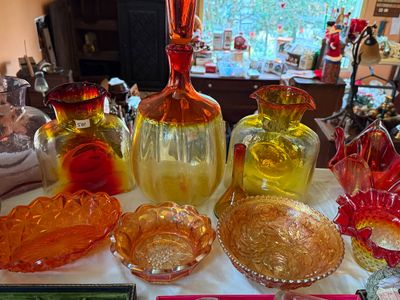 Sale Photo Thumbnail #56: Collection of vintage amberina glass and marigold carnival glass pieces, including decanters, pitchers, bowls, and a ruffled Fenton vase.