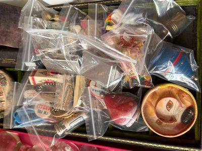 Sale Photo Thumbnail #58: Collection of vintage small trinkets, souvenirs, and novelty items individually packaged in plastic bags, arranged inside a green velvet-lined box.
