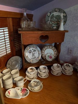 Sale Photo Thumbnail #105: Rustic wooden shelf displaying decorative transferware plates and glass decanters, accompanied by stacked vintage teacups and matching saucers on a wooden surface.