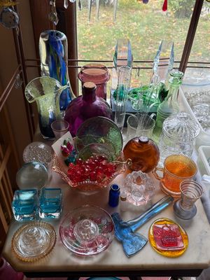 Sale Photo Thumbnail #37: Collection of vintage art glass items, including colorful vases, paperweights, decorative bowls, suncatchers, and novelty pieces set near a window.