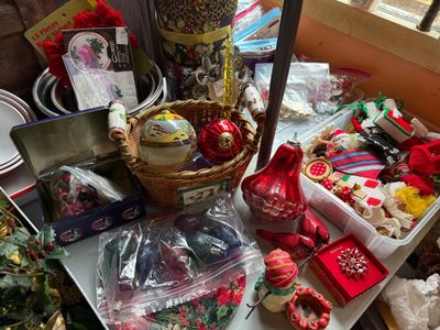 Sale Photo Thumbnail #125: Collection of holiday decorations, including glass Christmas tree ornaments, a woven basket, a bag of C9 light bulbs, a decorative poinsettia brooch in a box, and various handmade felt ornaments.
