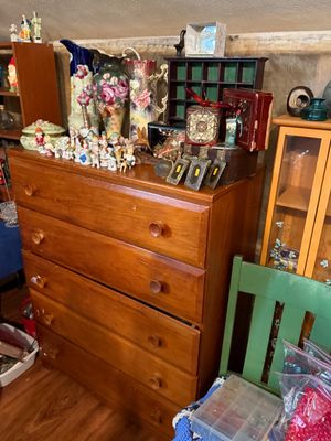 Sale Photo Thumbnail #89: Vintage four-drawer wooden dresser loaded with collectibles, including floral ceramic pitchers, small figurines, decorative boxes, and a shadowbox display.