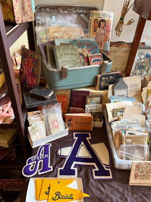 Sale Photo Thumbnail #78: Collection of vintage ephemera including antique children's books inside a train case, varsity felt letter patches, small pennants, and old photos.