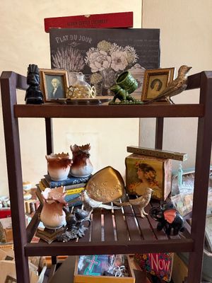 Sale Photo Thumbnail #73: Wooden display shelf filled with vintage knick-knacks, including small framed portraits, metal bird figurines, porcelain moose toothpicks, and decorative boxes.