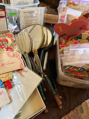 Sale Photo Thumbnail #77: Collection of vintage ephemera and vanity items, including hand mirrors, clothes brushes, curling irons, and plastic storage containers filled with antique Valentine's Day paper scraps.