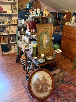 Sale Photo Thumbnail #86: Collection of vintage decor and artwork, featuring an oval shadowbox frame with pressed flowers, framed portrait prints, glassware, and wooden furniture.