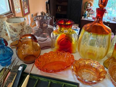 Sale Photo Thumbnail #60: Collection of vintage art glass pieces, featuring mid-century blown glass vases, decanters, pitchers, and orange carnival glass bowls.