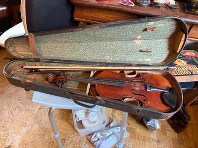 Sale Photo Thumbnail #151: Vintage violin with two bows inside an open hard case lined with patterned green paper, showing heavy wear and age.