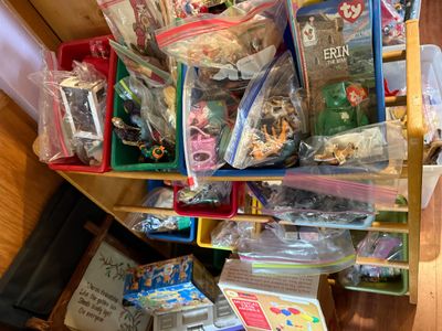 Sale Photo Thumbnail #94: Wooden toy rack organizer filled with colorful plastic bins containing assorted bagged small toys, including a Ty Beanie Baby and various figurines.
