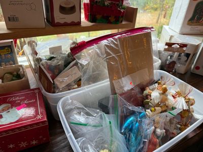 Sale Photo Thumbnail #137: Plastic storage bins filled with vintage Christmas ornaments, bagged figurines, and boxed holiday collectibles, including Department 56 items.