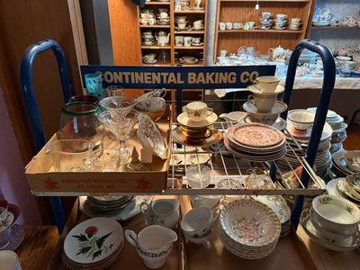Sale Photo Thumbnail #107: Vintage blue metal rack marked 'Continental Baking Co.' loaded with assortment of glassware, teacups, saucers, and china sets.