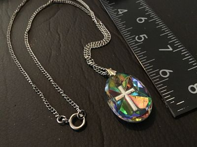 Sale Photo Thumbnail #34: Vintage silver-tone curb chain necklace featuring an oval pendant with an iridescent, stained-glass style multi-color cross design on one side and a faceted metallic cross motif on the reverse. Pendant measures approximately 1.25 inches long. Features a s