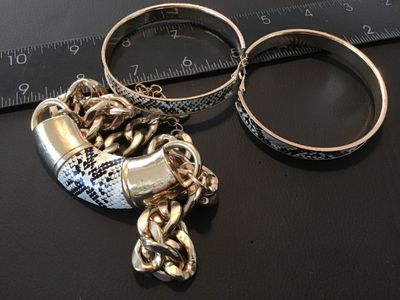Sale Photo Thumbnail #100: Matching costume jewelry set including a chunky gold-tone curb chain necklace with a snakeskin pattern curved center accent, and a pair of matching snakeskin pattern hoop earrings. Items show light wear consistent with use.