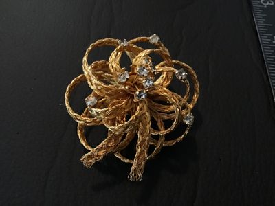 Sale Photo Thumbnail #21: Vintage gold-tone floral brooch featuring braided wire loops accents and set with clear rhinestones. Marked 'DIRECTION ONE' on an oval plaque on the back. Features a standard pin stem and roll-over safety clasp. In good vintage condition with light finish