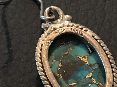 Sale Photo Thumbnail #102: Pair of sterling silver dangle/drop earrings featuring oval composite blue turquoise stones with brass/copper matrix. Detailed with rope trim and bead accents. Stamped '925' and 'INDIA' on the back. Measures approximately 1.25 inches long including fishho