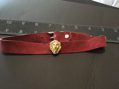 Sale Photo Thumbnail #108: Vintage burgundy red suede leather choker or belt-style band featuring a gold-tone lion head medallion at the center. Secured with a silver-tone buckle closure and screw-back attachment for the charm. Measures approximately 12 to 14 inches long. Shows lig