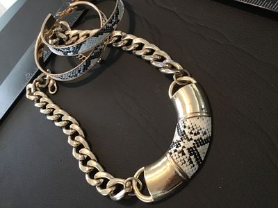 Sale Photo Thumbnail #99: Matching costume jewelry set including a chunky gold-tone curb chain necklace with a snakeskin pattern curved center accent, and a pair of matching snakeskin pattern hoop earrings. Items show light wear consistent with use.