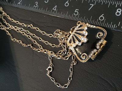 Sale Photo Thumbnail #59: gold-tone chain necklace featuring an ornate purse-shaped locket pendant with black enamel work and clear rhinestone accents. The locket opens on a bottom hinge with a textured gold-tone interior. Pendant measures approximately 1.5 inches wide by 1.25 inc