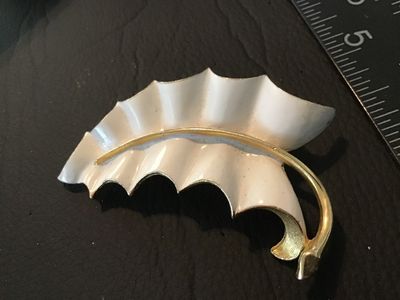 Sale Photo Thumbnail #60: A vintage white enamel and gold-tone metal brooch styled as a ruffled leaf. Features a textured gold-tone back with a standard pin stem and rollover safety clasp. Measures approximately 2.5 inches long. Pre-owned condition with minor signs of surface wear