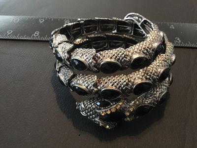 Sale Photo Thumbnail #118: Textured silver-tone snake wrap bracelet featuring black tear-shaped cabochon stones and small yellow crystal accents around the snake head. Stretch band design with coiled body effect. Good pre-owned condition with minor surface wear. Measures approximat