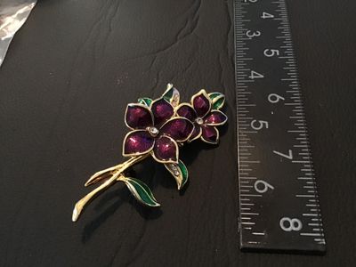 Sale Photo Thumbnail #44: A gold-tone brooch featuring purple enamel flower blooms, green enamel leaves, and clear rhinestone accents. Measures approximately 2.5 inches long. Features a standard pin back with standard clasp. In good condition with light wear.