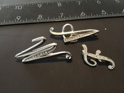 Sale Photo Thumbnail #113: Set of three silver-tone initial letter brooches featuring the letters 'M', 'A', and 'F'. Each brooch is set with clear rhinestones in a script design with pin-back closures. Brooches measure approximately 1.25 to 2.25 inches in height. Items show light w