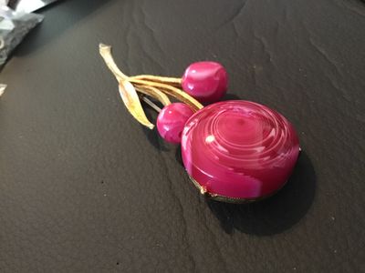 Sale Photo Thumbnail #41: Vintage gold-tone textured metal brooch featuring a floral/stem design with a large pink-and-white swirl glass or cabochon flower head and matching pink accent beads. Standard rollover safety clasp on the back. Measures approximately 2.5 inches in length.
