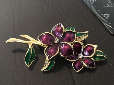 Sale Photo Thumbnail #42: A gold-tone brooch featuring purple enamel flower blooms, green enamel leaves, and clear rhinestone accents. Measures approximately 2.5 inches long. Features a standard pin back with standard clasp. In good condition with light wear.