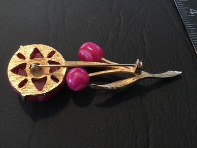 Sale Photo Thumbnail #40: Vintage gold-tone textured metal brooch featuring a floral/stem design with a large pink-and-white swirl glass or cabochon flower head and matching pink accent beads. Standard rollover safety clasp on the back. Measures approximately 2.5 inches in length.