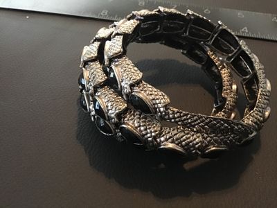Sale Photo Thumbnail #120: Textured silver-tone snake wrap bracelet featuring black tear-shaped cabochon stones and small yellow crystal accents around the snake head. Stretch band design with coiled body effect. Good pre-owned condition with minor surface wear. Measures approximat
