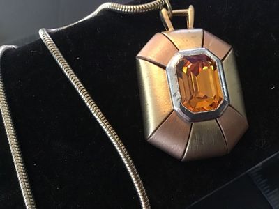 Sale Photo Thumbnail #67: Vintage Napier costume jewelry necklace featuring an emerald-cut amber/citrine color glass or rhinestone centerpiece set in a silver-tone bezel. The geometric pendant features alternating gold-tone and rose gold-tone panels with a textured back stamped wi
