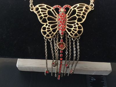 Sale Photo Thumbnail #36: Statement necklace featuring a large openwork butterfly focal piece adorned with red rhinestones and hanging chain fringe with rhinestone drops. Marked 'PILGRIM' on the back of the butterfly and 'DANISH DESIGN' on the metal tag near the clasp. Features a 