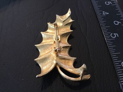 Sale Photo Thumbnail #61: A vintage white enamel and gold-tone metal brooch styled as a ruffled leaf. Features a textured gold-tone back with a standard pin stem and rollover safety clasp. Measures approximately 2.5 inches long. Pre-owned condition with minor signs of surface wear