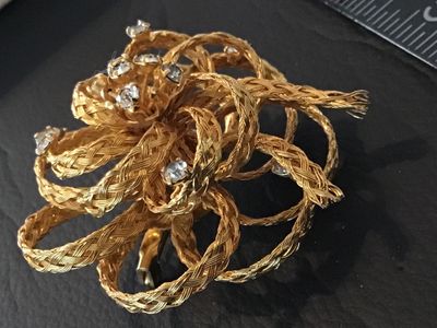 Sale Photo Thumbnail #24: Vintage gold-tone floral brooch featuring braided wire loops accents and set with clear rhinestones. Marked 'DIRECTION ONE' on an oval plaque on the back. Features a standard pin stem and roll-over safety clasp. In good vintage condition with light finish
