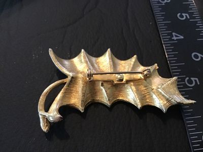Sale Photo Thumbnail #62: A vintage white enamel and gold-tone metal brooch styled as a ruffled leaf. Features a textured gold-tone back with a standard pin stem and rollover safety clasp. Measures approximately 2.5 inches long. Pre-owned condition with minor signs of surface wear