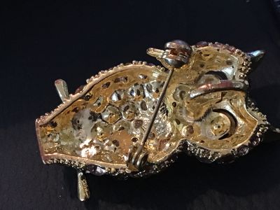 Sale Photo Thumbnail #31: Gold tone owl-shaped brooch featuring paved brown and champagne-colored rhinestones with dark amber glass accents for the ears and beak. Measures approximately 1.5 inches in length. Features a rollover safety clasp on the back. Good pre-owned condition wi