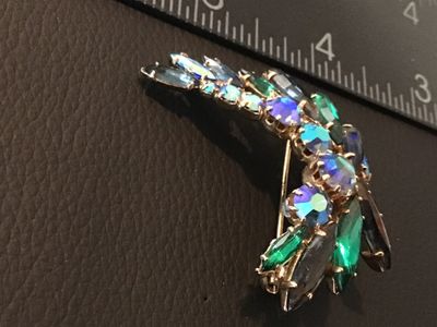 Sale Photo Thumbnail #3: A vintage costume jewelry brooch featuring blue, green, and iridescent aurora borealis rhinestones in a stylized winged or floral spray setting. The back is stamped 'CZECHO SLOVAKIA'. Measures approximately 2 inches wide. Pin clasp on the reverse is intac